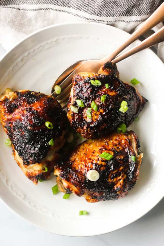 bbq chicken thighs cooked in air fryer on a white plate