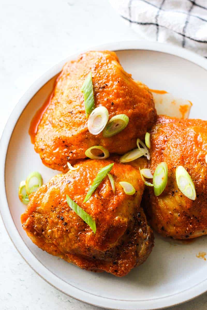 air fryer buffalo chicken thighs with green onions on top on the grey plate