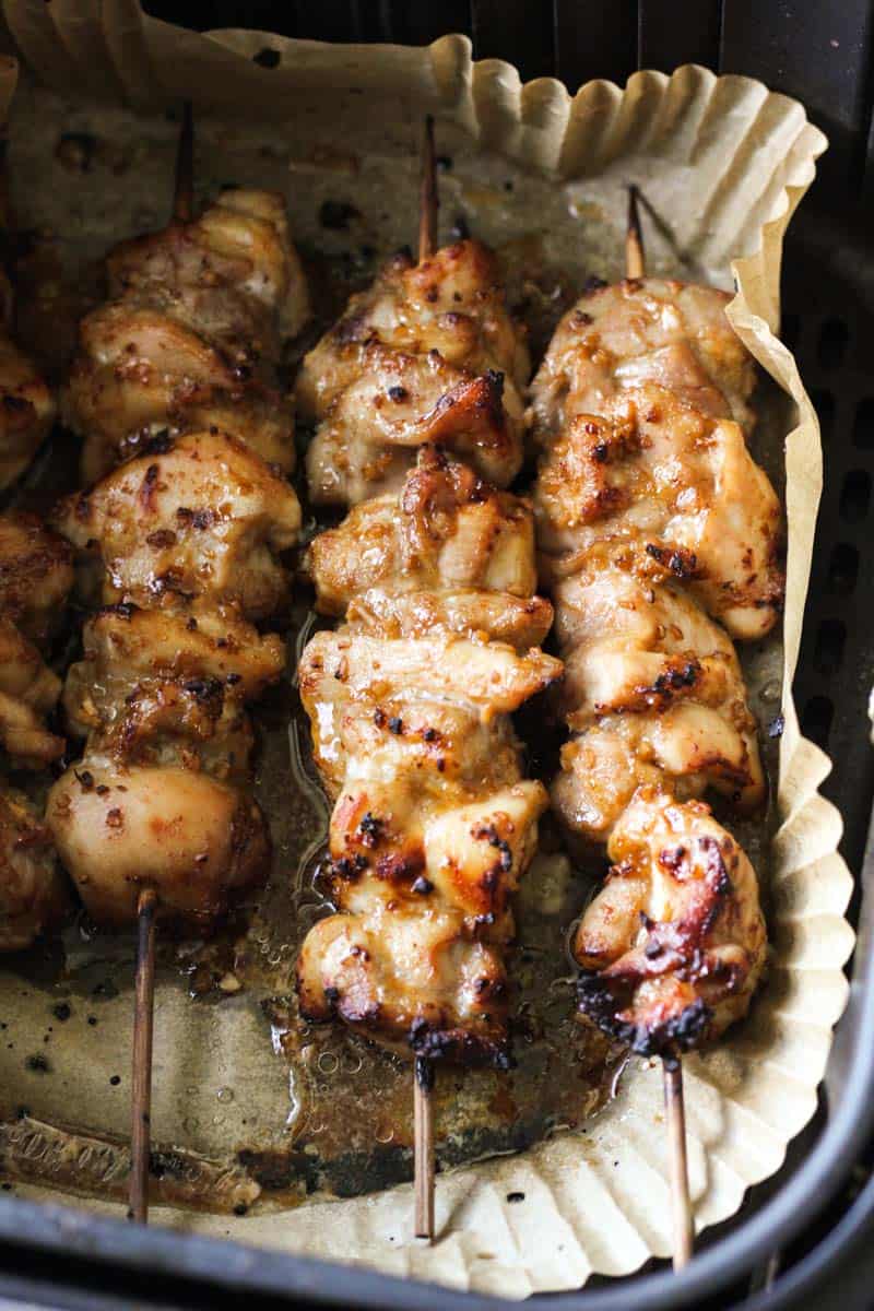 chicken kebabs in the air fryer basket lined with parchment paper