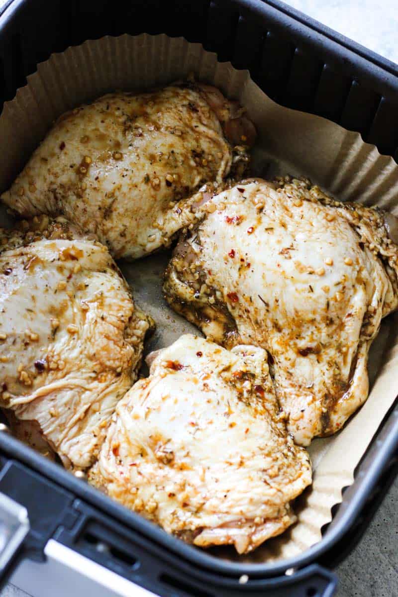 raw chicken thighs covered in jerk seasoning in air fryer