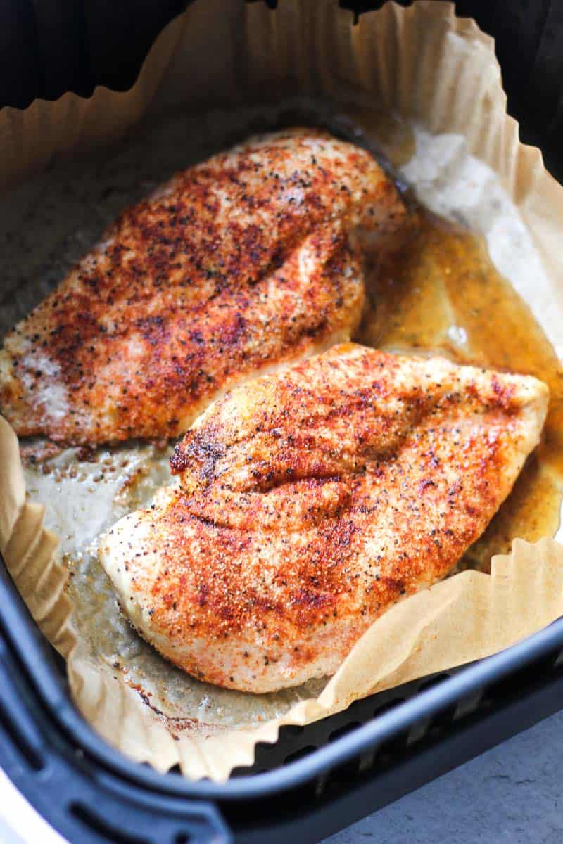 two seasoned chicken breasts in air fryer