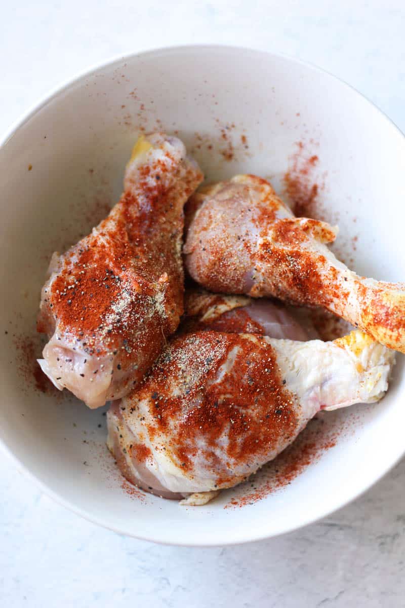 raw drumsticks with seasoning in the white bowl