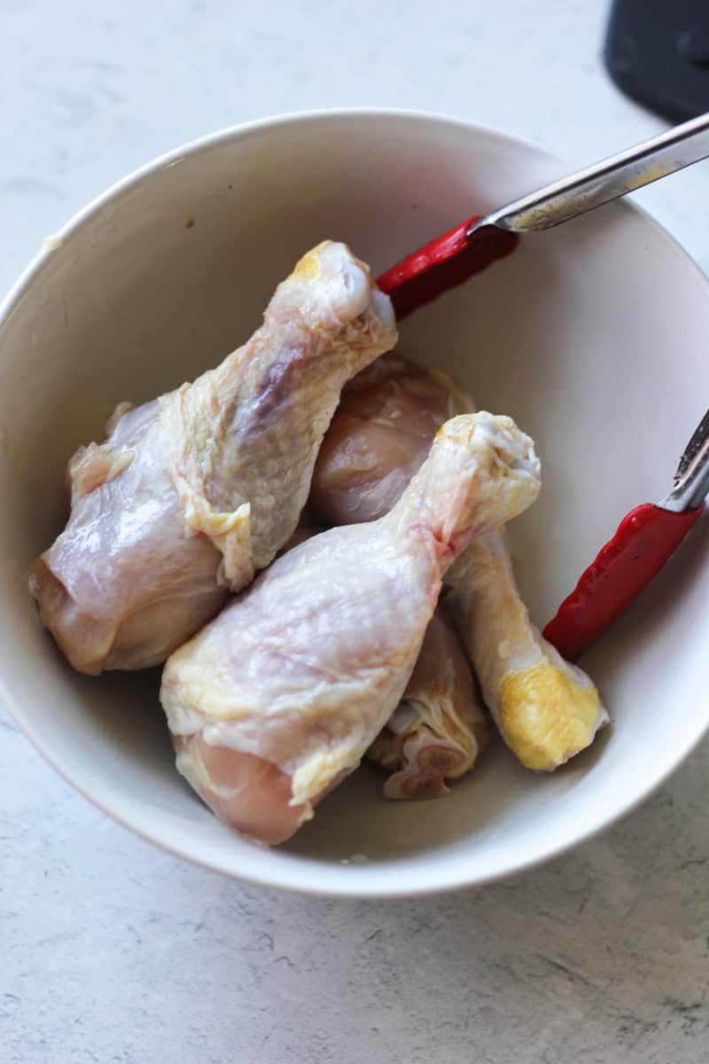 raw chicken drumsticks in the white bowl