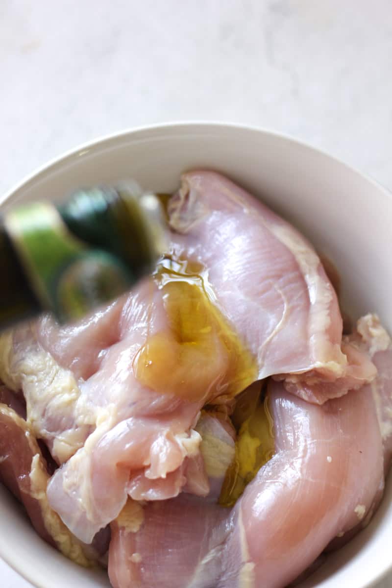 pouring olive oil on top of chicken