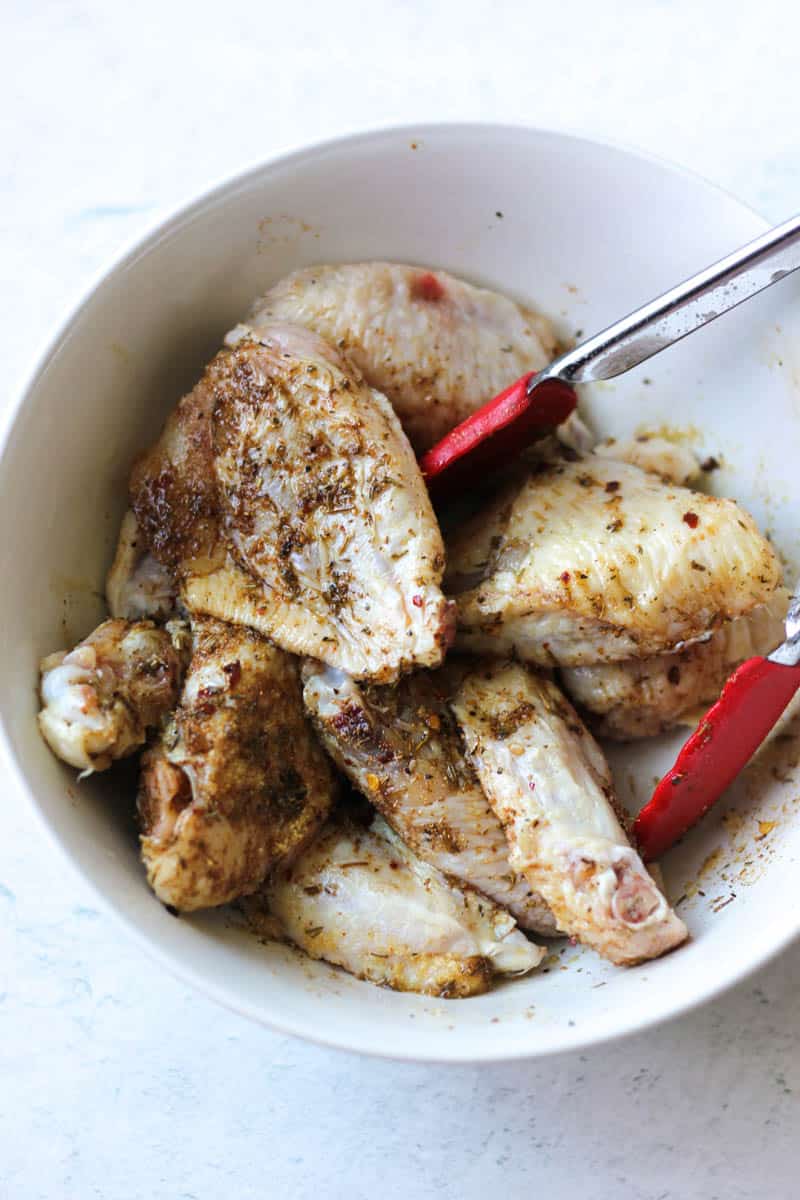 chicken wings with seasonings in the white bowl