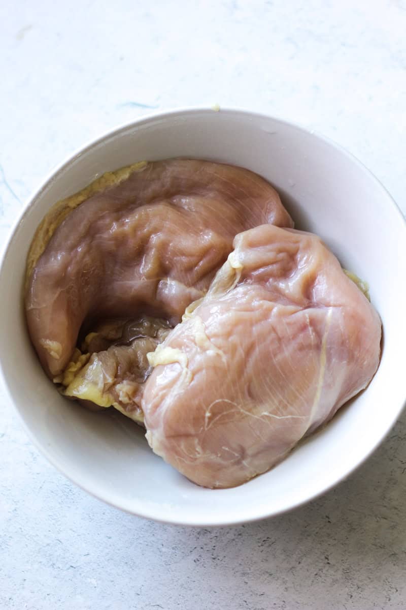 whole raw chicken breast in the white bowl