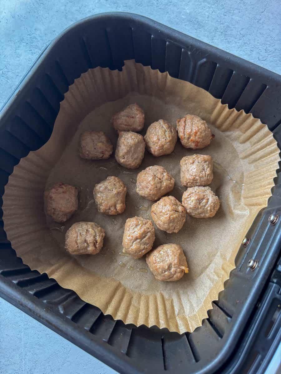 uncooked meatballs in air fryer basket