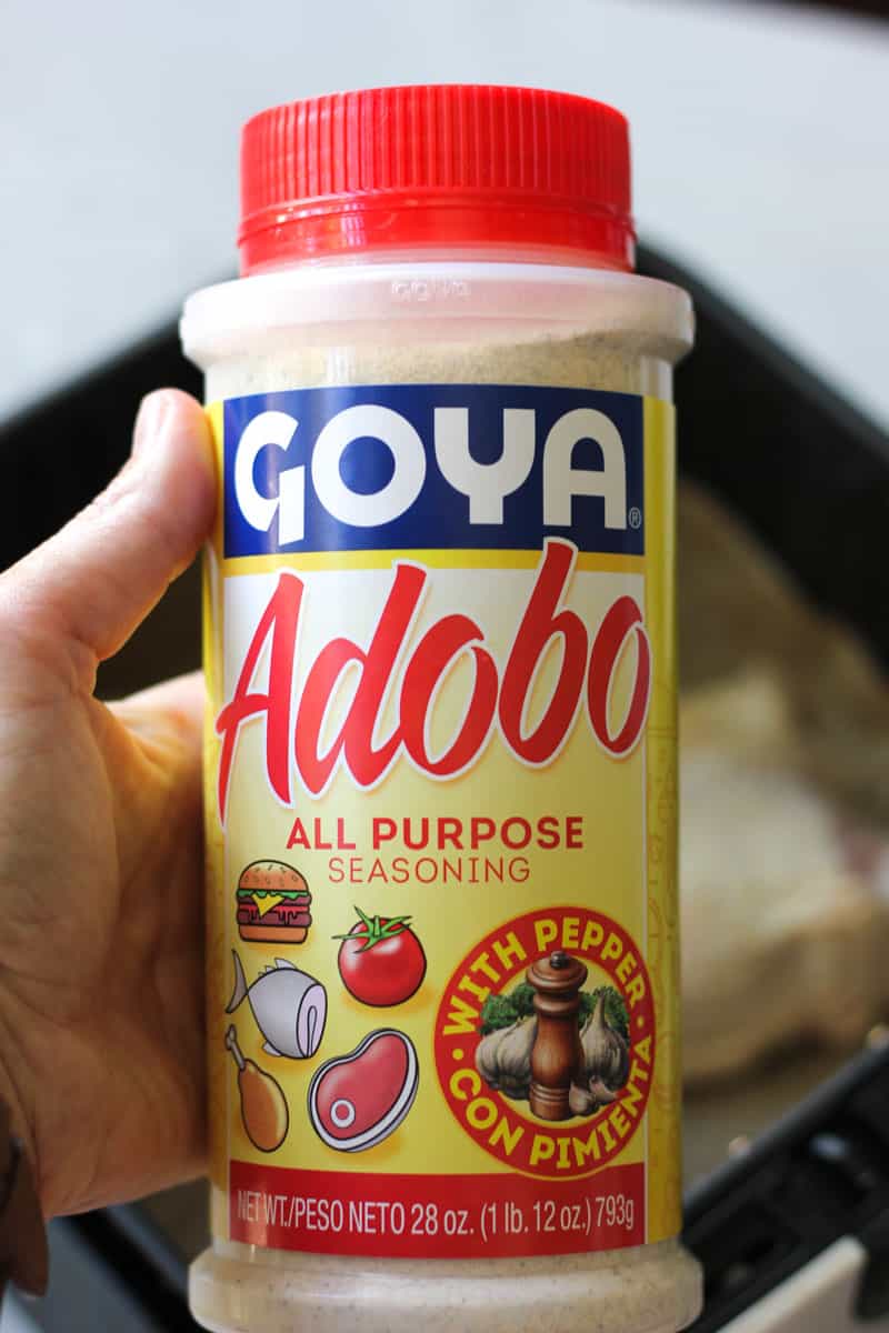 adobo seasoning in the plastic container in hand