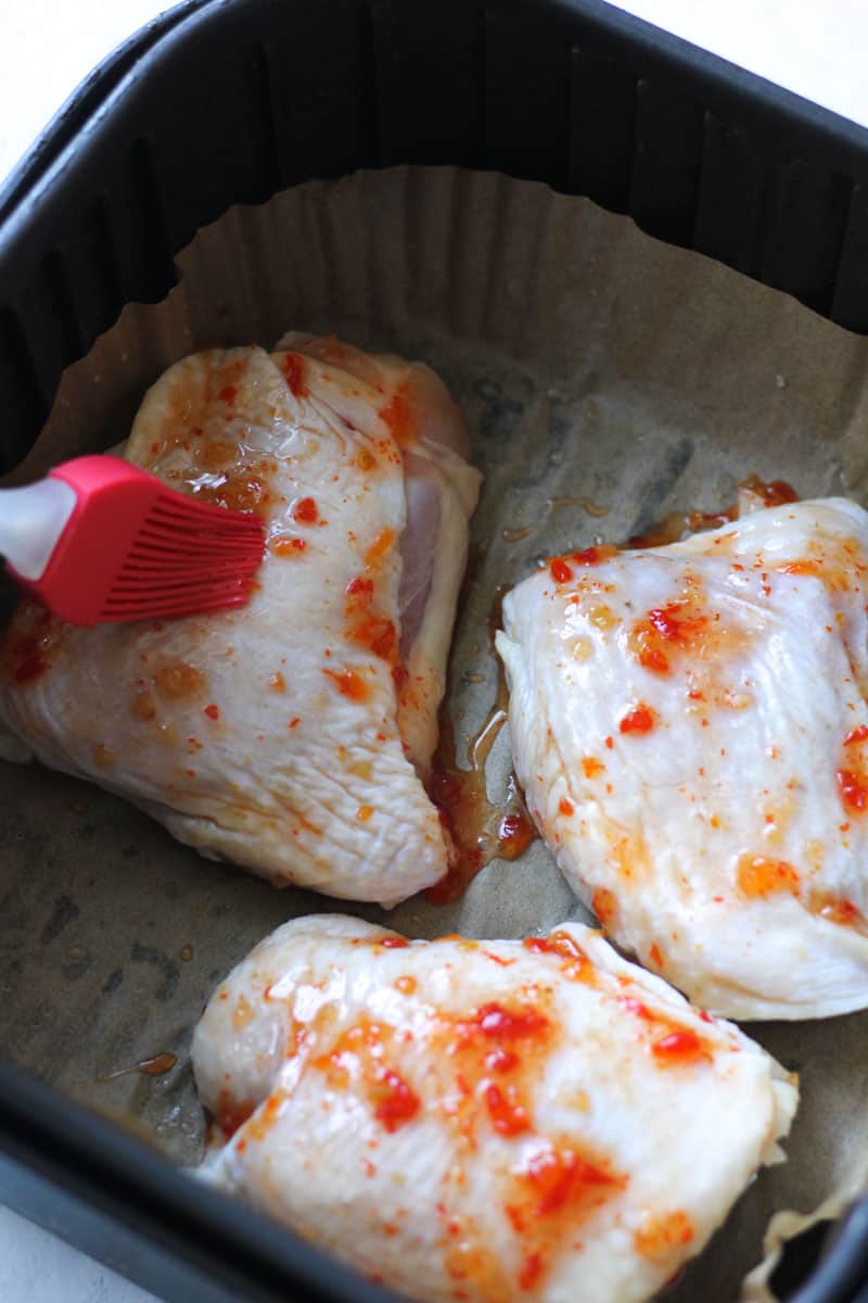 brushing sweet chili sauce on raw chicken