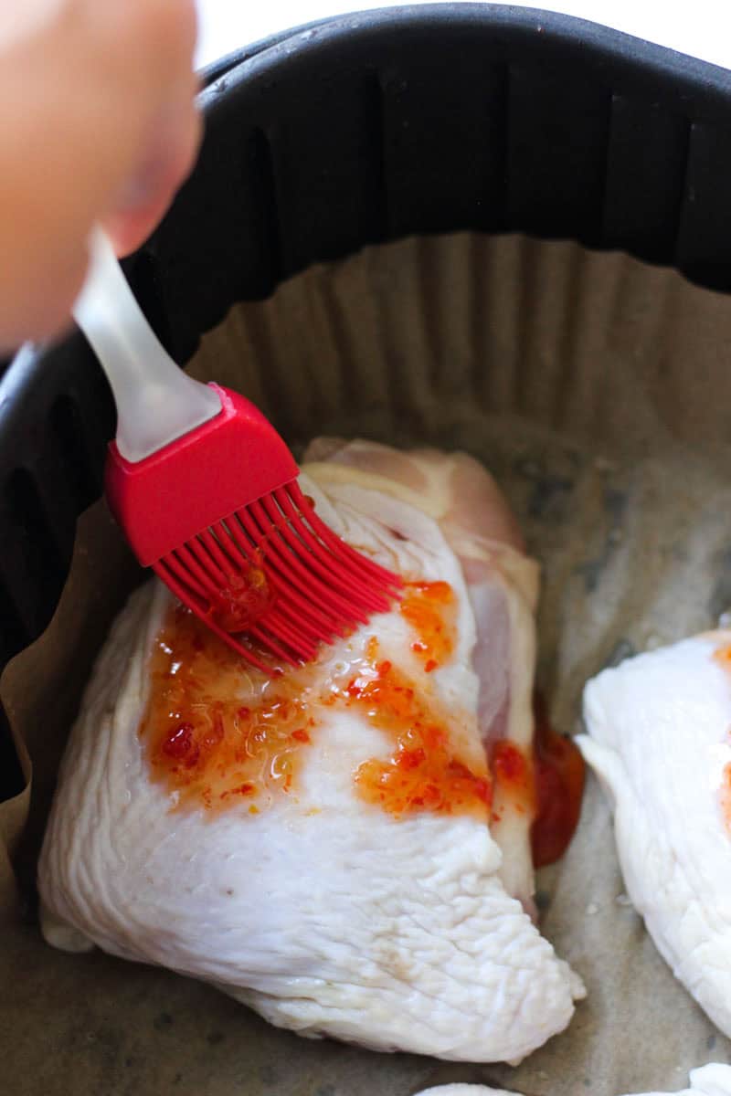 brushing sweet chili sauce on raw chicken