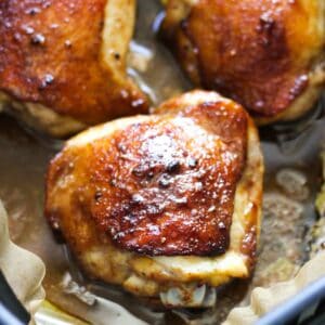 chicken thighs cooked in the air fryer with crispy brown skin covered in maple sauce