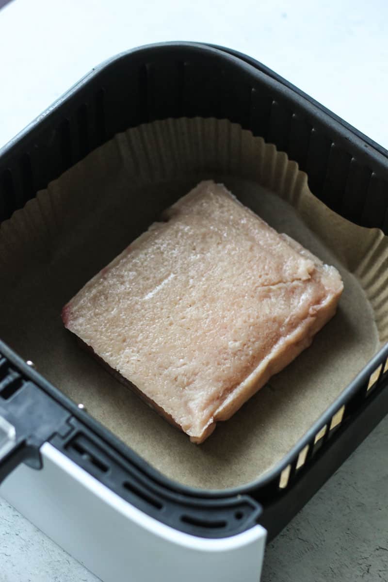 a block of chicken in the air fryer basket